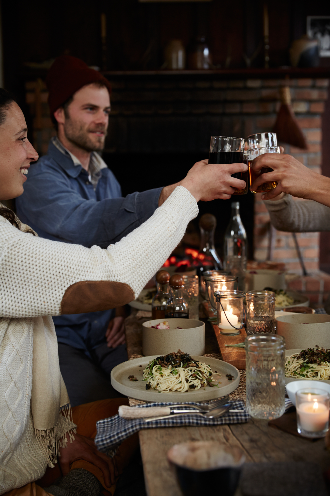 Friends toasting with glasses around a candlelit dinner table in a rustic dining room