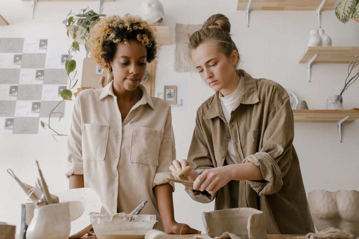 Two women making ceramics together in a bright pottery studio
